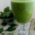 Pineapple Almond Milk Smoothie in a cup with spinach leaves in the background.