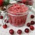 A glass jar of cranberry sugar scrub on a white and red background.