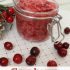 A glass jar of cranberry sugar scrub on a white and red background, with text reading "Cranberry sugar scrub".