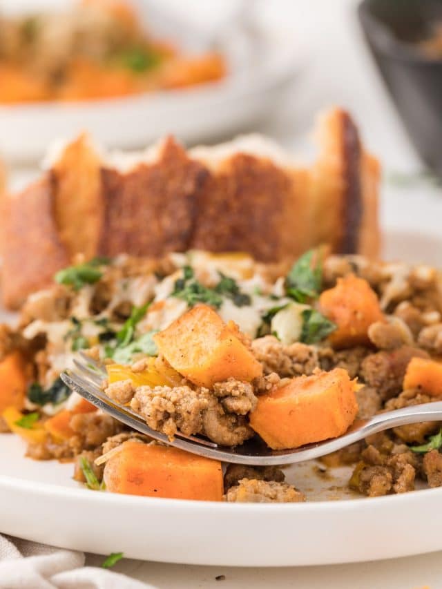A closeup view of a plate of food, with a forkful of sweet potatoes, ground turkey, and bell pepper.