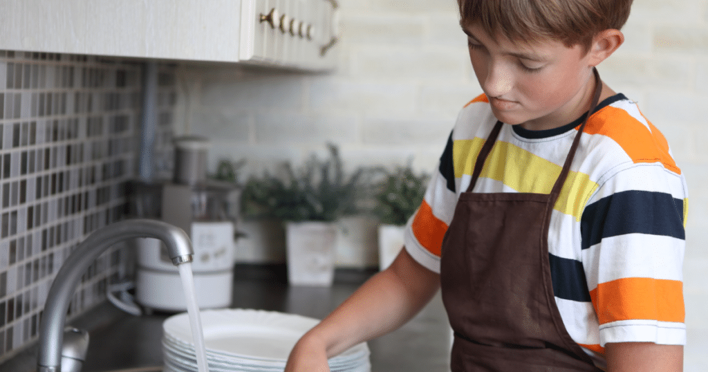 Boy helping with chores by washing dishes.