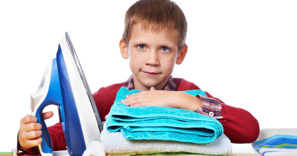 Boy sitting with folded towels and an iron.