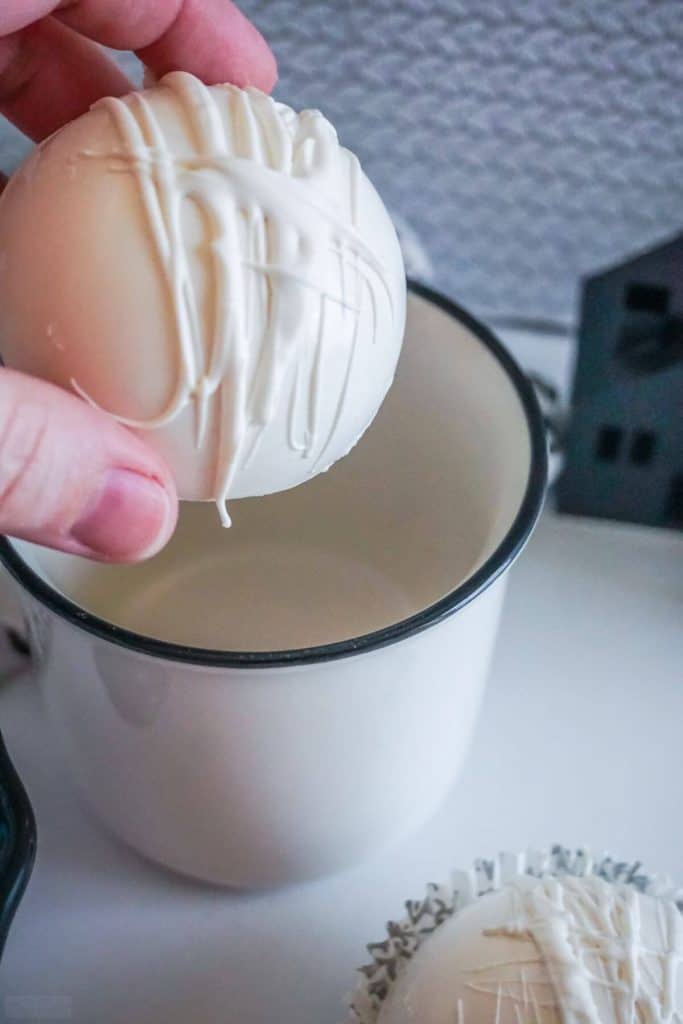 White chocolate coffee bomb being held above a coffee cup