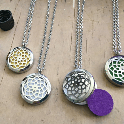 4 diffuser necklaces laying on a table.