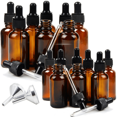 Collection of amber essential oil bottles, dropper lids, and two silver funnels on a white background.