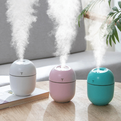 3 mini diffusers on a desk in front of a plant.