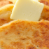 A closeup of a stack of tattie scones, topped with butter.