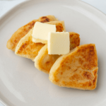 A plate with four Scottish potato scones topped with butter.