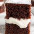 Closeup view of creamy marshmallow filling between two slices of devils food cake, with text naming the recipe a copycat Hostess Suzy Q.