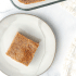 A square of cornbread on a plate with a pan of cornbread beside it and text saying "homemade paleo cornbread".
