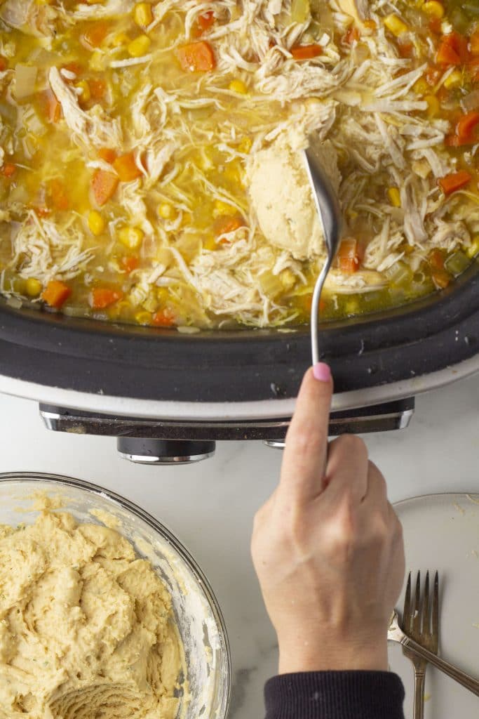 Add spoonfuls of drop dumplings into a slow cooker.
