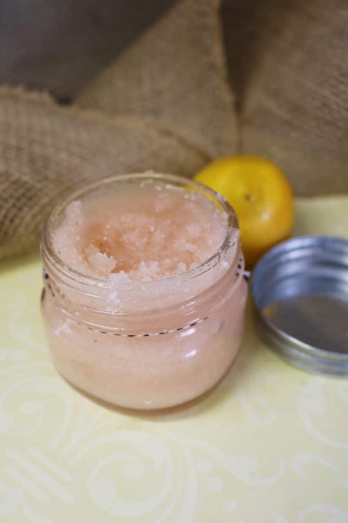 Grapefruit sugar scrub in a glass jar with the lid next to it.