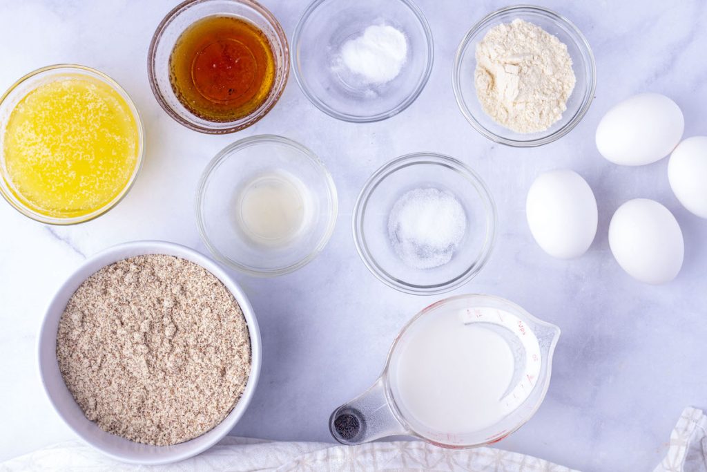 Ingredients for paleo cornbread in small bowls and a measuring cup on a countertop.