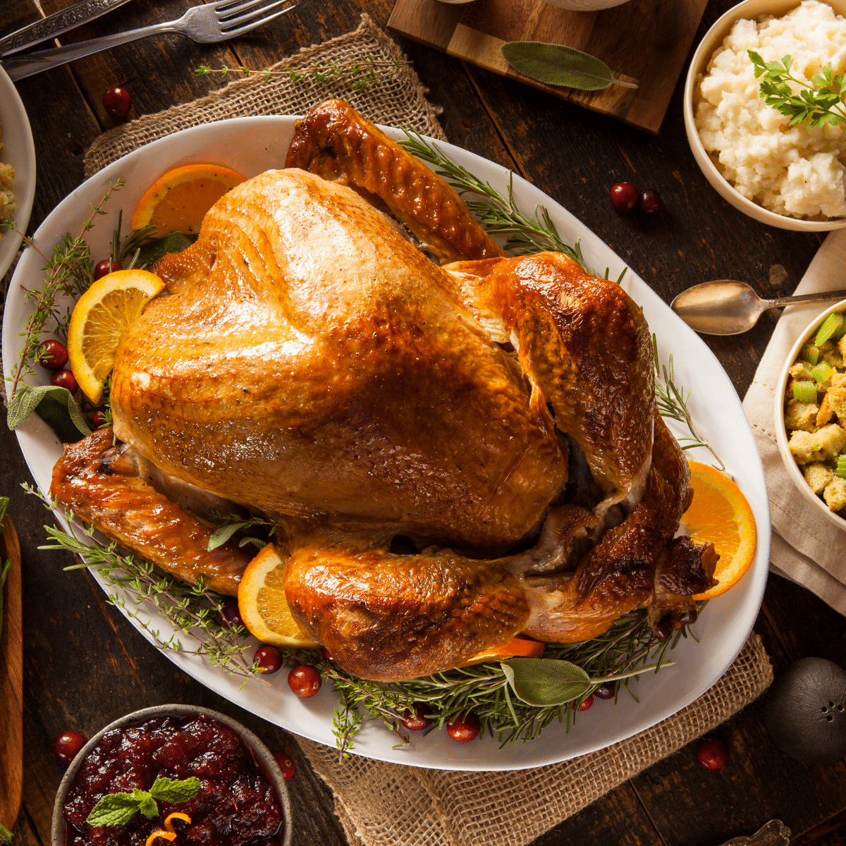 Thanksgiving turkey on a platter surrounded by side dishes.