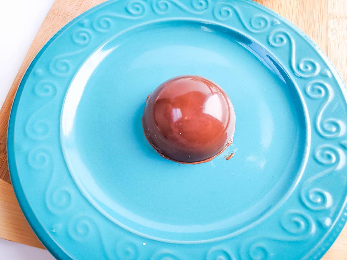 A blue plate with a chocolate half-shell sits on a wooden cutting board.