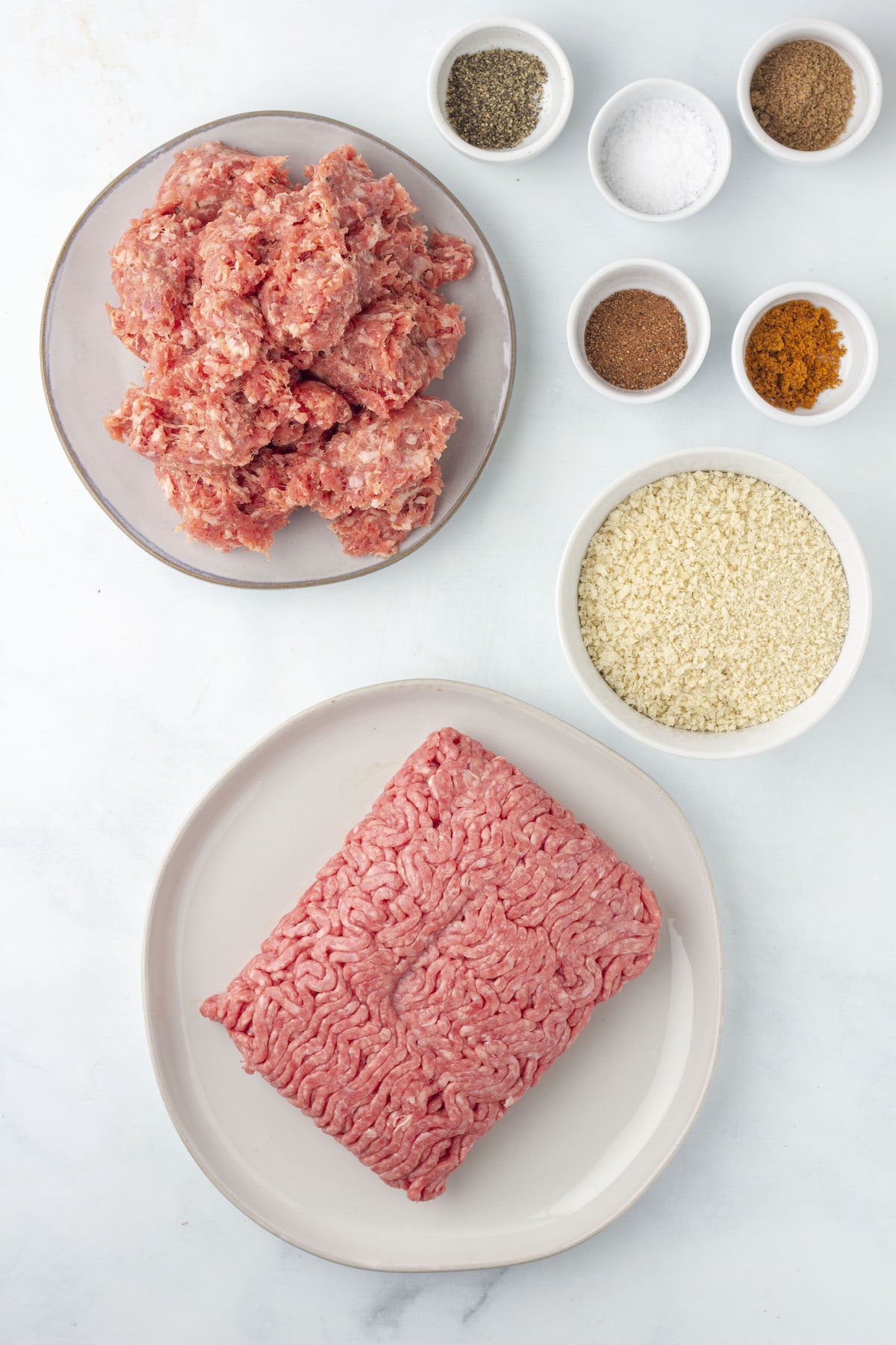 Ingredients for square sausage, including two types of ground meat, breadcrumbs, and spices in bowls.
