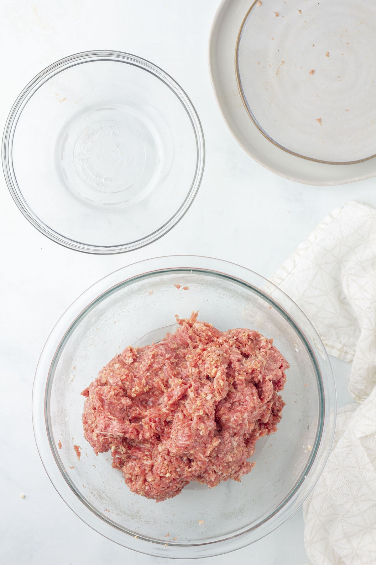 Ground meat mixed with seasoned breadcrumbs in a glass bowl.
