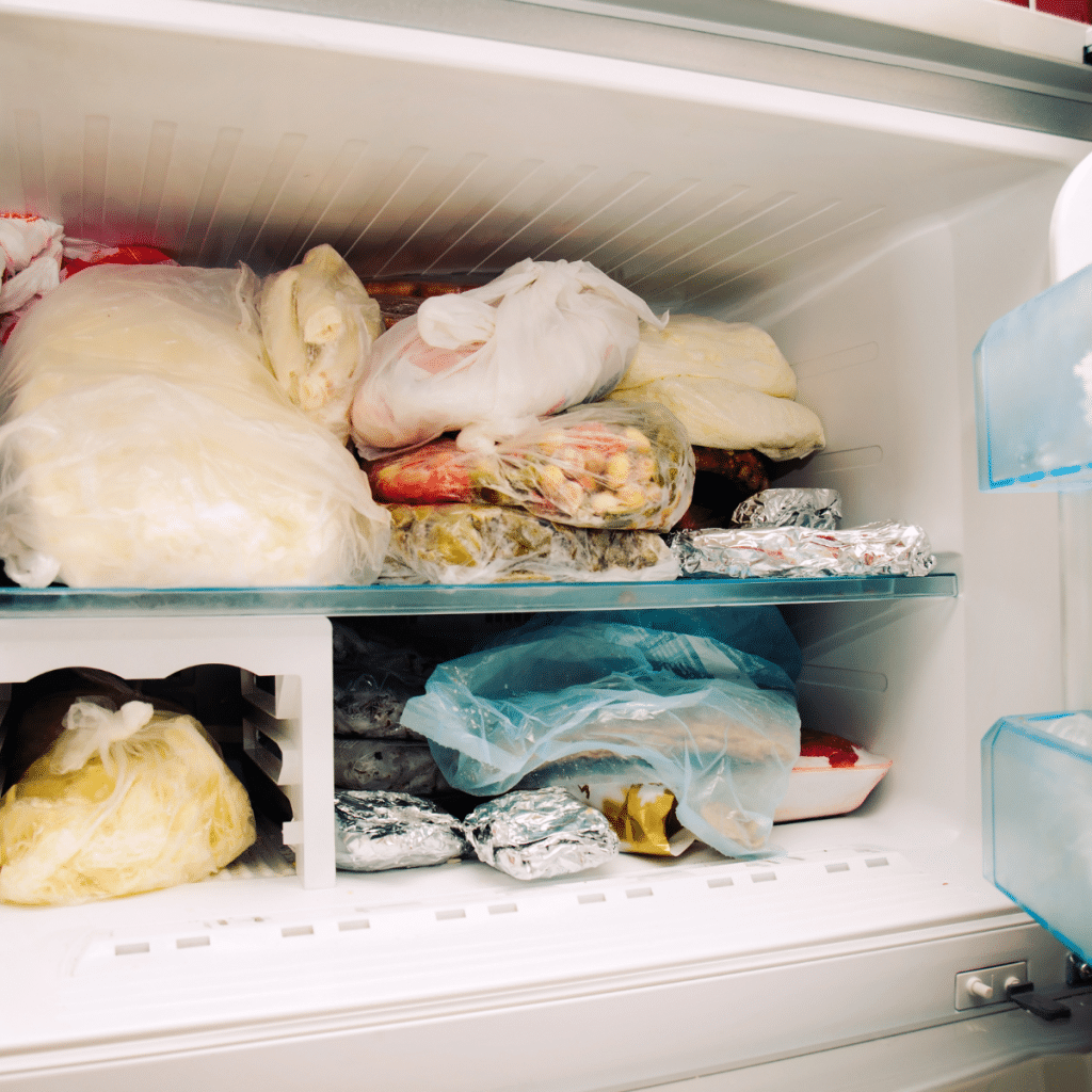 Inside of messy freezer with items haphazardly wrapped and randomly placed.