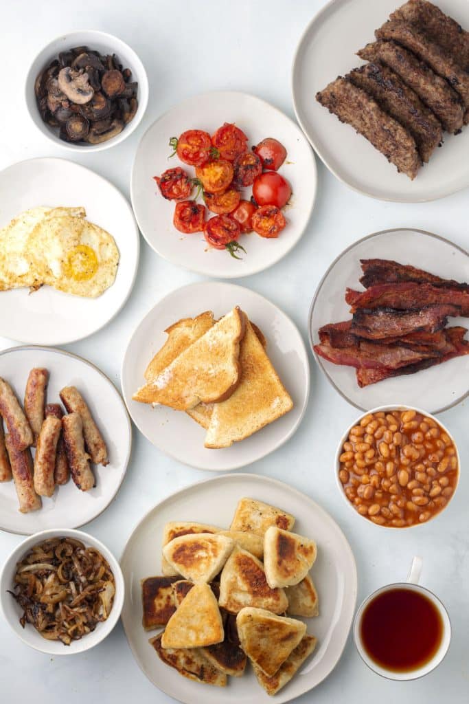 Plates of Scottish breakfast foods on a white table.