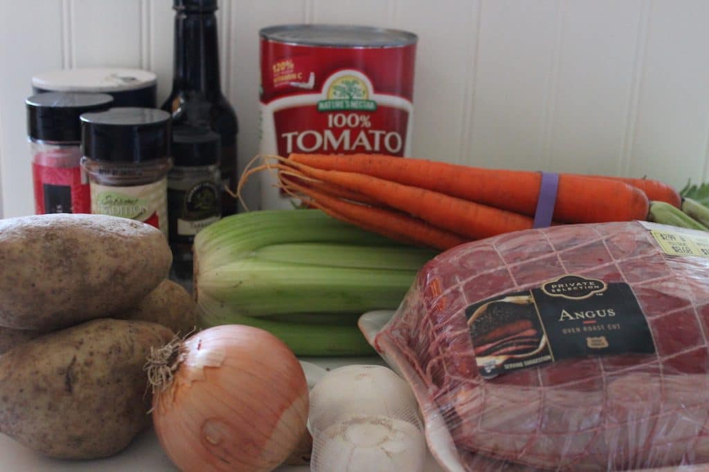An assortment of meat, vegetables, and spices on a counter for beef stew.