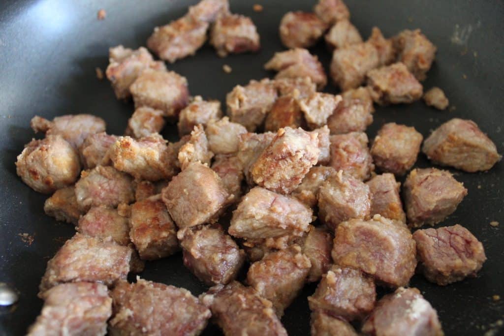 Browned cubes of beef in a skillet.