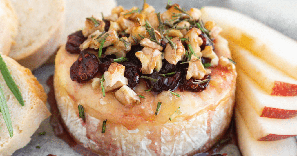 A wheel of brie, topped with cranberries, honey, walnuts, and rosemary.